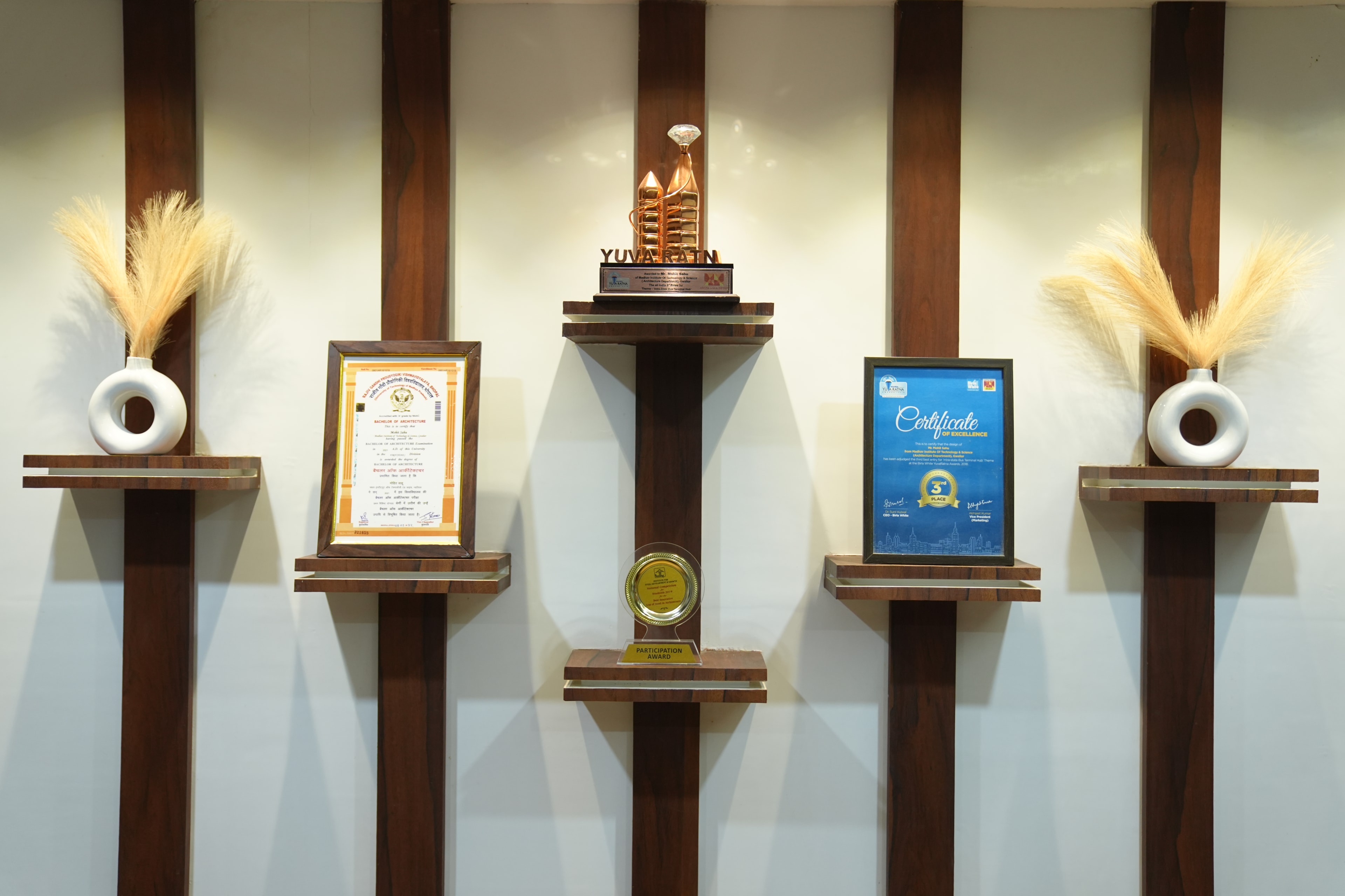 The studio's wall of recognition — the Yuva Ratna trophy, an INSDAG certificate, and other honours on display.
