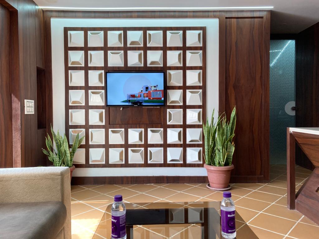 Studio reception — a sculpted three-dimensional tile feature wall with snake plants framing an architectural render on screen.